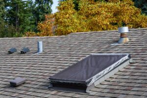 A homeowner examines a newly installed roof while reviewing maintenance documents beside a suburban house.
