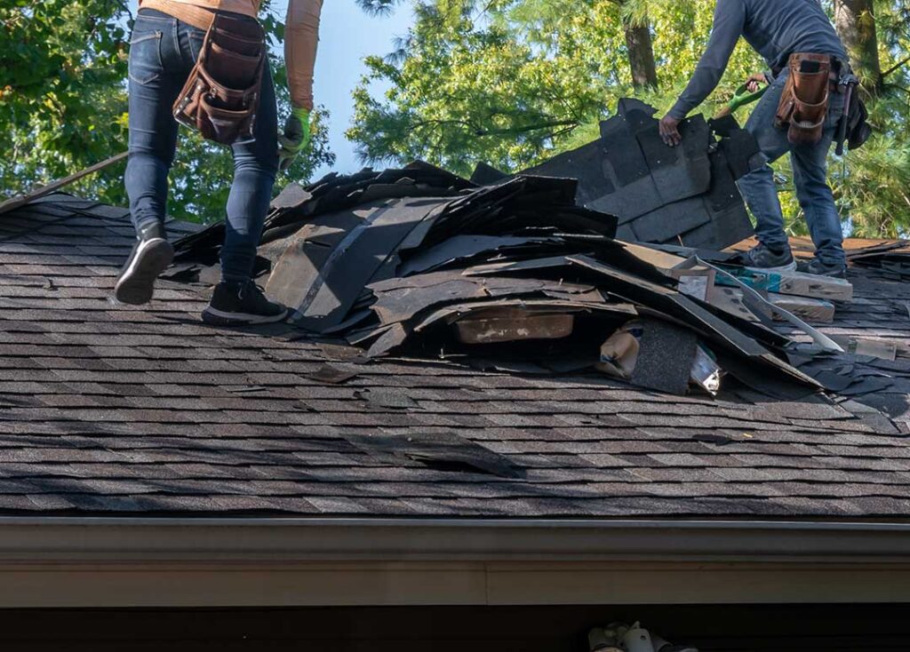 Homeowner reviews roofing financing papers at a kitchen table beside a calculator and roof repair documents.